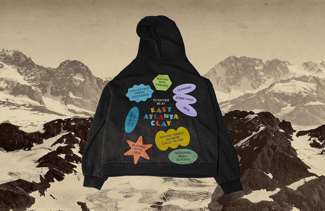 A hoodie mockup with a very playful, colourful design reading "I'd rather be at East Atlanta Clay... collecting happy accidents, making new friends, learning something new, laughing 'til I cry, making "vases" my mom calls blobs, playing with mud, gossiping while glazing"