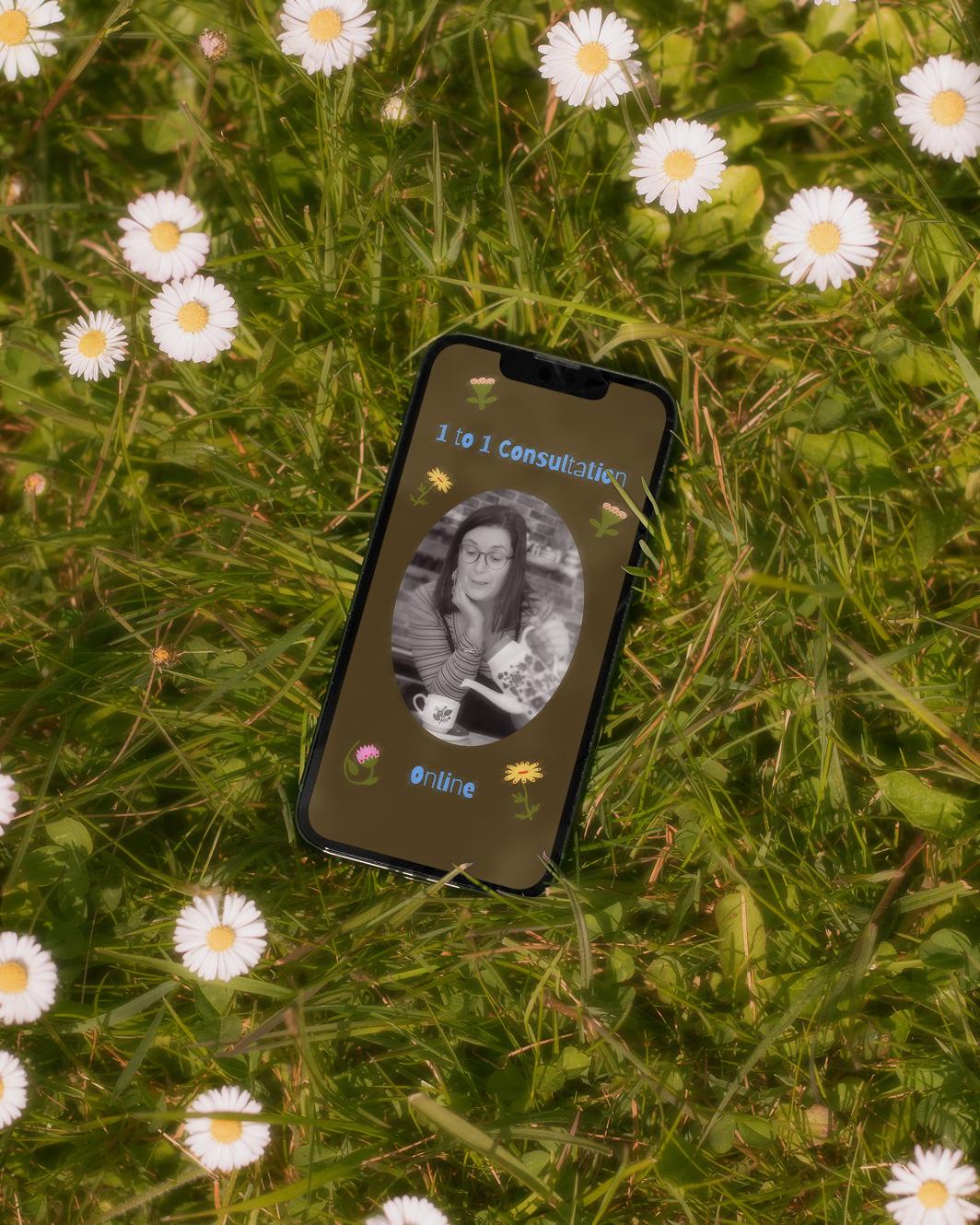 An iPhone with a custom designed Instagram graphic pulled up, lying in the grass that's decorated with daisies; the mood is dreamy, a bit hazy